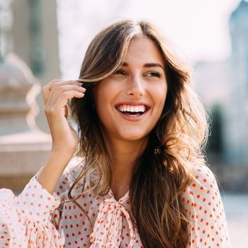 Eine glückliche und freie Frau, lächelnd. Sie hat People Pleasing abgelegt.